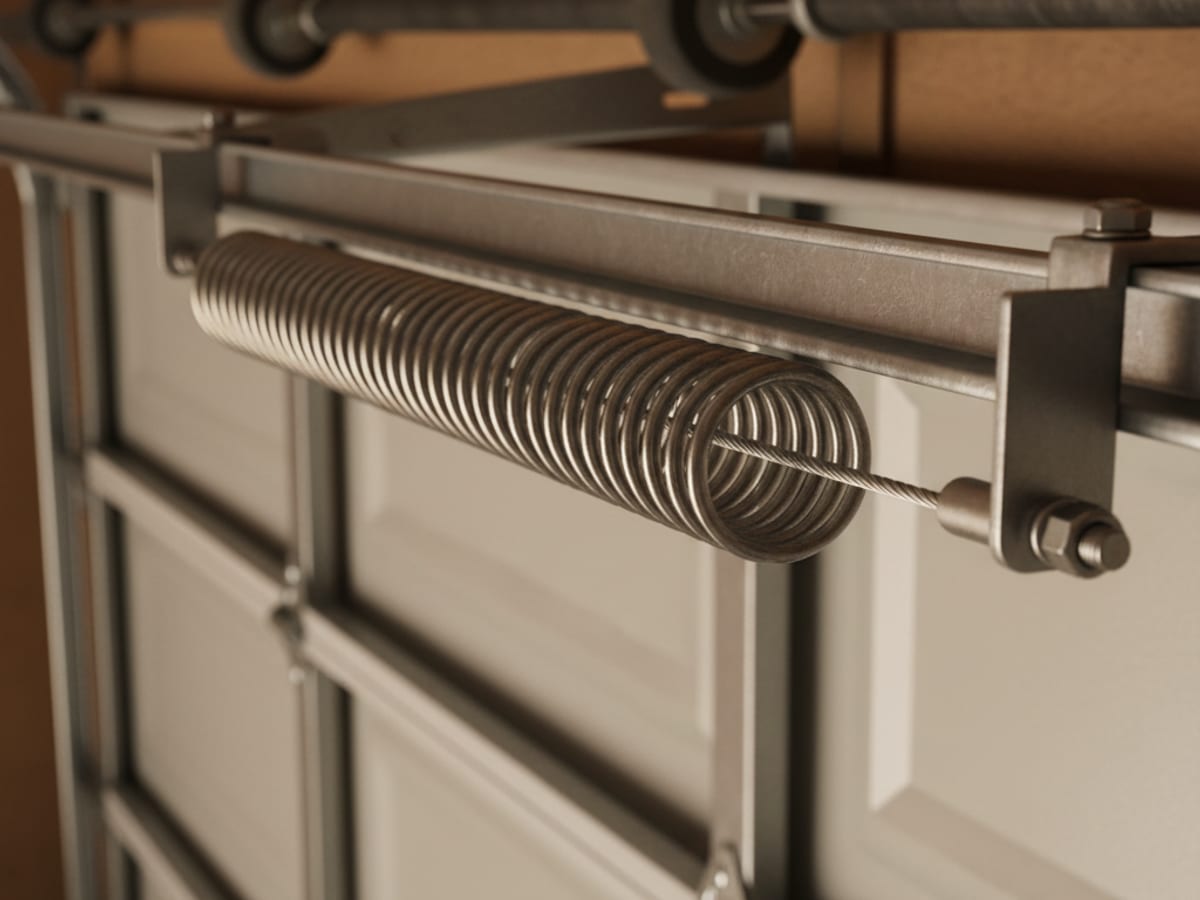 Close-up of a steel safety cable threaded through the center of an extension spring mounted along a horizontal garage door track