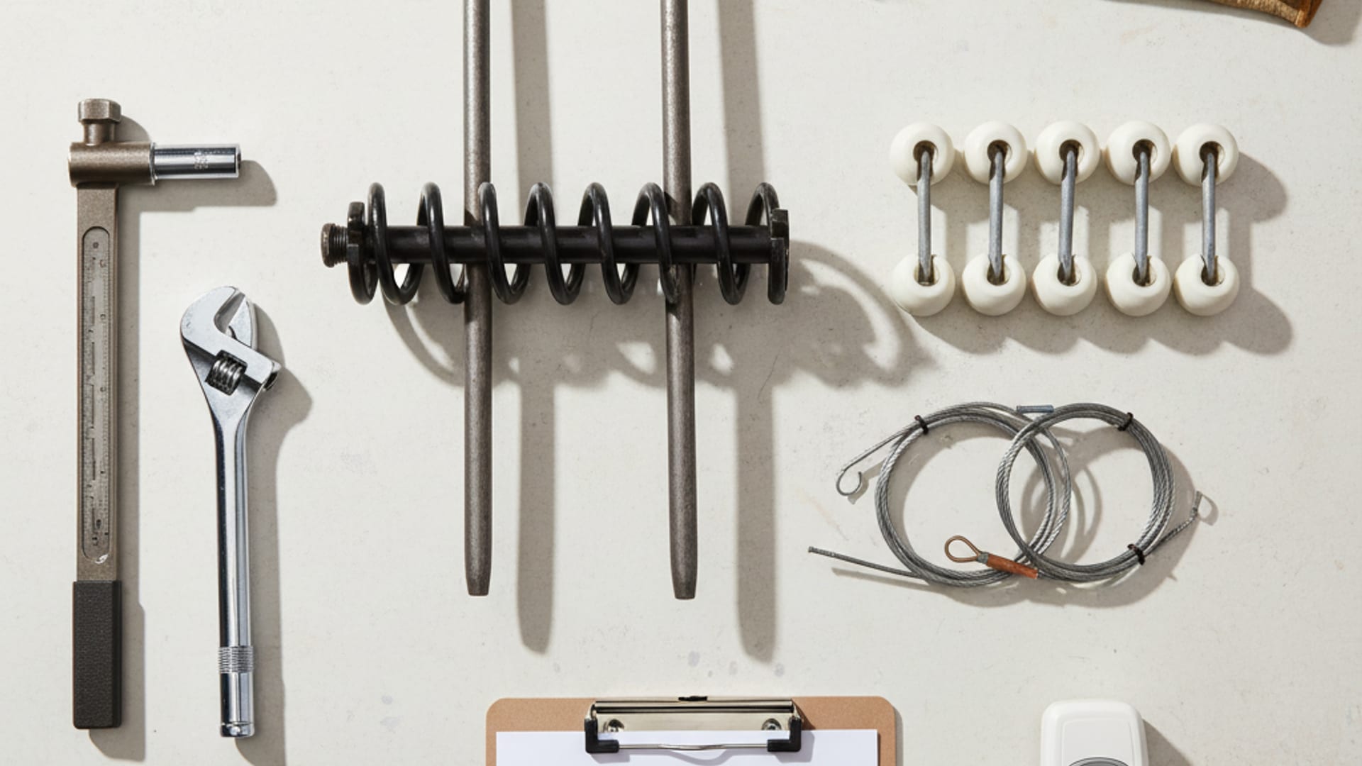 Overhead flat-lay of professional garage door service equipment including refrigerant gauges, multimeter, capacitors, and tools on a clean work surface